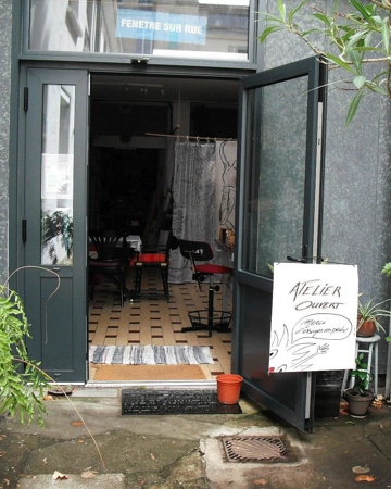Porte de l'atelier invitant à entrée grâce au panneau "ouvert" pour une accessibilité à tous.